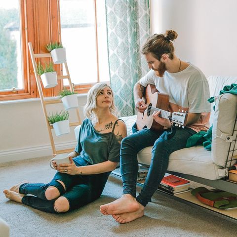 Ein junges Paar, der Mann spielt Gitarre