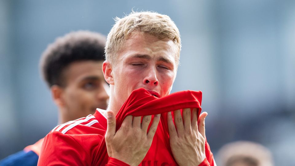 HSV-Spieler Jann-Fiete Arp zieht den Saum seines roten HSV-Trikots mit beiden Händen zum Gesicht