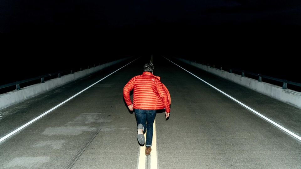 Mann läuft auf dunkler Straße