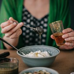 Frau tut Honig auf ihr Müsli