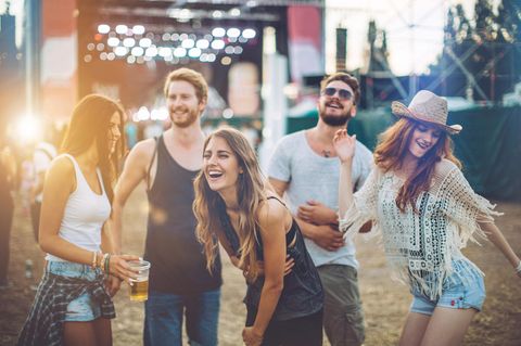 Drei Frauen und zwei Männer tanzen auf einem Festival.