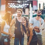 Drei Frauen und zwei Männer tanzen auf einem Festival.