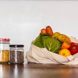 Einmachgläser mit Nüssen, Linsen und ein Beutel mit frischem Gemüse.