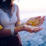 Frauenhände, die mit goldenem Glitzer spielen.