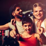 Zwei Männer und eine Frau lachen und tanzen gemeinsam.