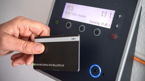 Arbeitszeiterfassung. Ein Mitarbeiter erfasst seine Arbeitszeit digital an einem Terminal.