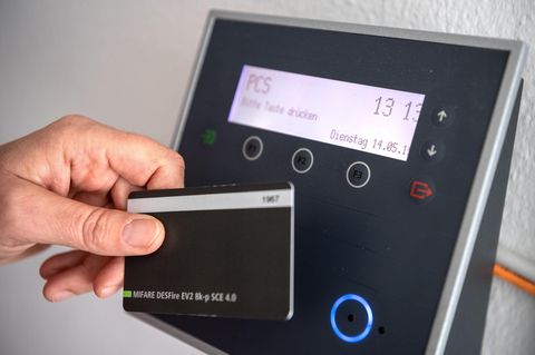 Arbeitszeiterfassung. Ein Mitarbeiter erfasst seine Arbeitszeit digital an einem Terminal.