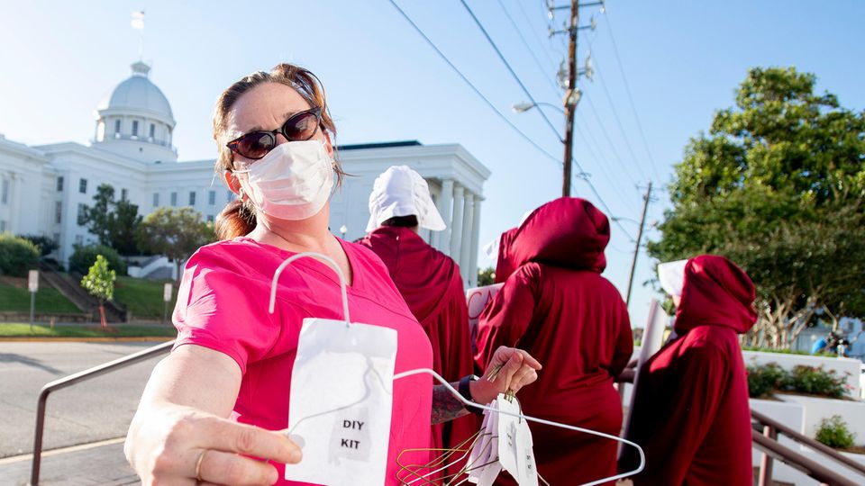 Frau Kleiderbügel Abtreibung Alabama Protest Eine Frau in pinker Klinik-Kleidung hält einen Draht-Kleiderbügel als Werkzeug für eine "Heim-Abtreibung" in der rechten Hand