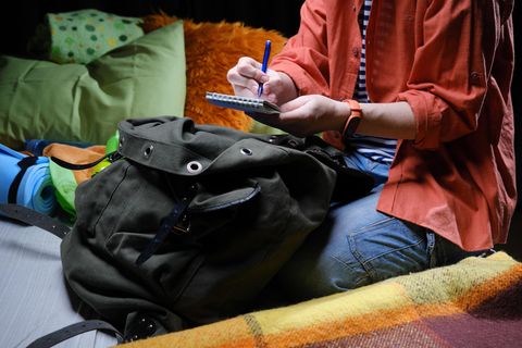 Eine Frau sitzt im Zelt und schreibt etwas auf