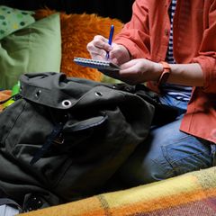 Eine Frau sitzt im Zelt und schreibt etwas auf