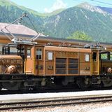 Nach acht Kilometern ist der Bahnhof von Bergün erreicht, wo gerade eine legendäre Lokomotive einen Nostalgiezug mit geschlossen Personen- und offenen Aussichtswagen zieht: das Krokodil. Im Hintergrund ist das Bahnmuseum Albula zu sehen.