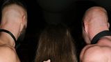 Eine Frau steht zwischen zwei mit Muskeln bepackten Männern