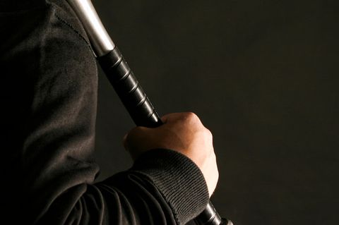 Eine Hand hält einen Baseballschläger im Dunkeln
