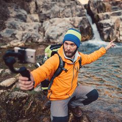 Ein Wanderer filmt sich selbst vor einem Wasserfall
