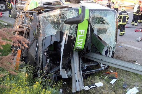 Sachsen, Leipzig: Einsatzkräfte der Feuerwehr stehen an der Unfallstelle neben dem verunglückten Bus auf der Autobahn 9
