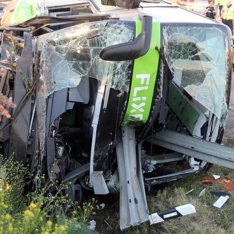 Sachsen, Leipzig: Einsatzkräfte der Feuerwehr stehen an der Unfallstelle neben dem verunglückten Bus auf der Autobahn 9