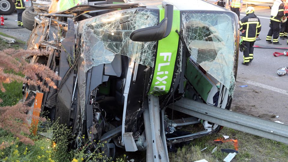 Sachsen, Leipzig: Einsatzkräfte der Feuerwehr stehen an der Unfallstelle neben dem verunglückten Bus auf der Autobahn 9