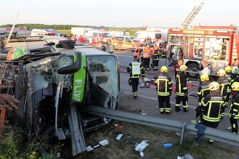 Einsatzkräfte der Feuerwehr stehen an der Unfallstelle auf der Autobahn 9 nahe Leipzig neben dem verunglückten Flixbus