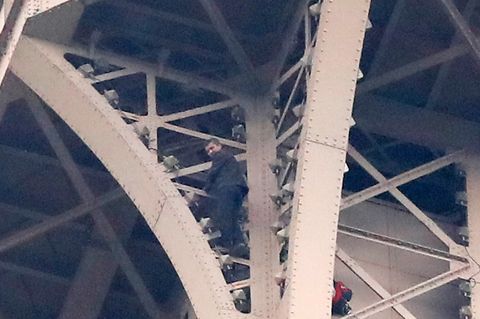 Ein Kletterer steht auf Eisenstreben hoch oben am Eifelturm