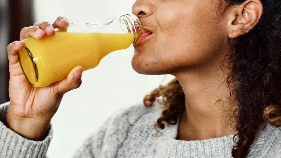 Gesundheitsgefahren von Fruchtsäften: Eine Frau trinkt Orangensaft