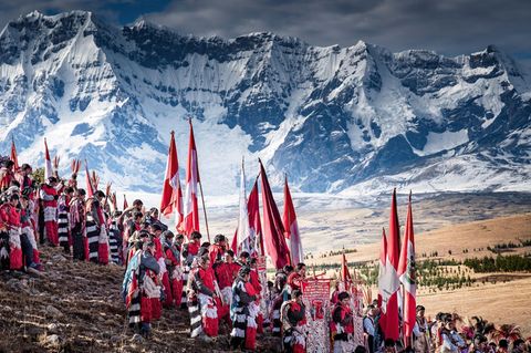 Peru / Berg-Wanderung  Fahnen, Essen, ein ganzes Zeltdorf tragen die Pilger den Berg Qullqip'unqu hinauf bis zu 4700 Meter Höhe. Hier feiern sie Fronleichnam. In die katholischen Riten mischen sich alte Traditionen der Sternanbetung für eine gute Ernte. Vom Berg brachten sie einst Blöcke des Gletschers – als Weihwasser. Das ist heute verboten, zu sehr ist das ewige Eis geschmolzen.
