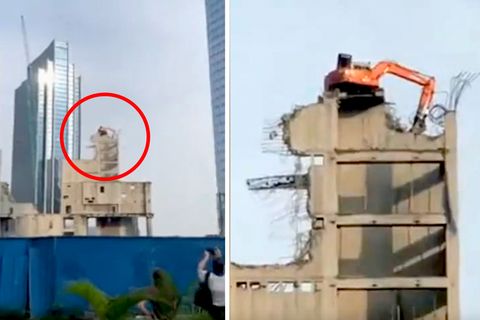 Ein Abrissbagger in Jakarta demontiert in luftiger Höhe das Hochhaus, auf dem er steht.