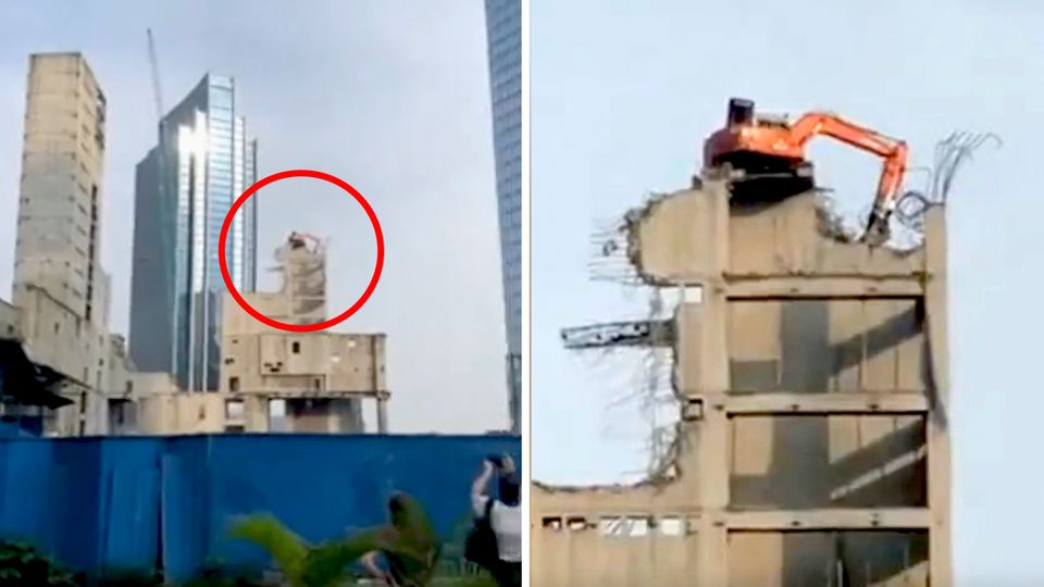 Ein Abrissbagger in Jakarta demontiert in luftiger Höhe das Hochhaus, auf dem er steht.
