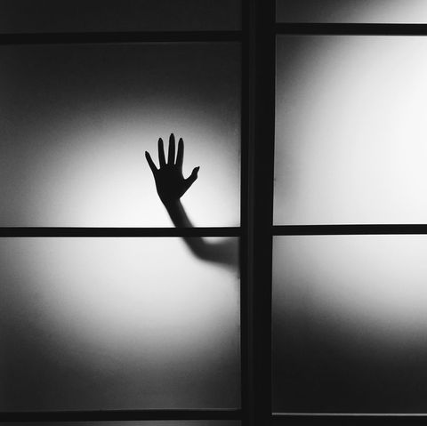 Hand hinter einer Glasscheibe