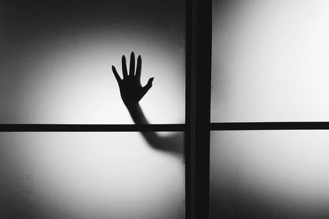 Hand hinter einer Glasscheibe