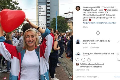 Blondes Mädchen in einer Menschenmenge mit einem herzförmigen Luftballon in der Hand.