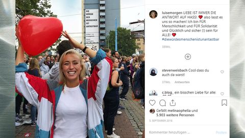 Blondes Mädchen in einer Menschenmenge mit einem herzförmigen Luftballon in der Hand.