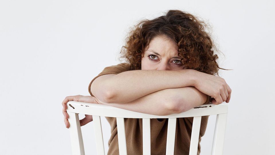 Traurige, junge Frau auf einem Stuhl