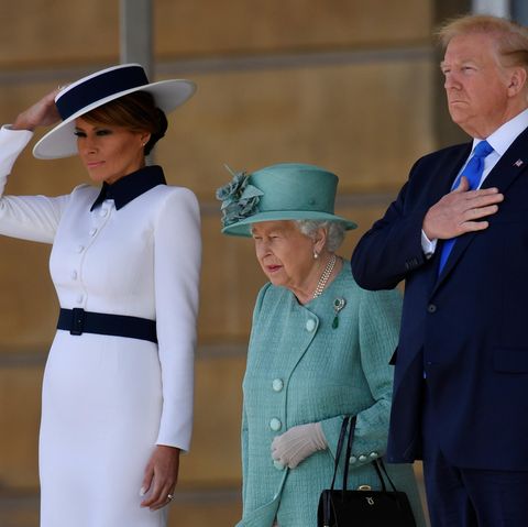 Die Hand gehört eigentlich nicht an den Hut: Melania Trump (l.) muss bei einem Windstoß nach oben greifen. Der Hut der Queen sitzt hingegen perfekt. Donald Trump bleibt unbeirrt.