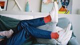 Beine in Jeans mit weißen Sneakers an den Füßen.