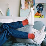 Beine in Jeans mit weißen Sneakers an den Füßen.