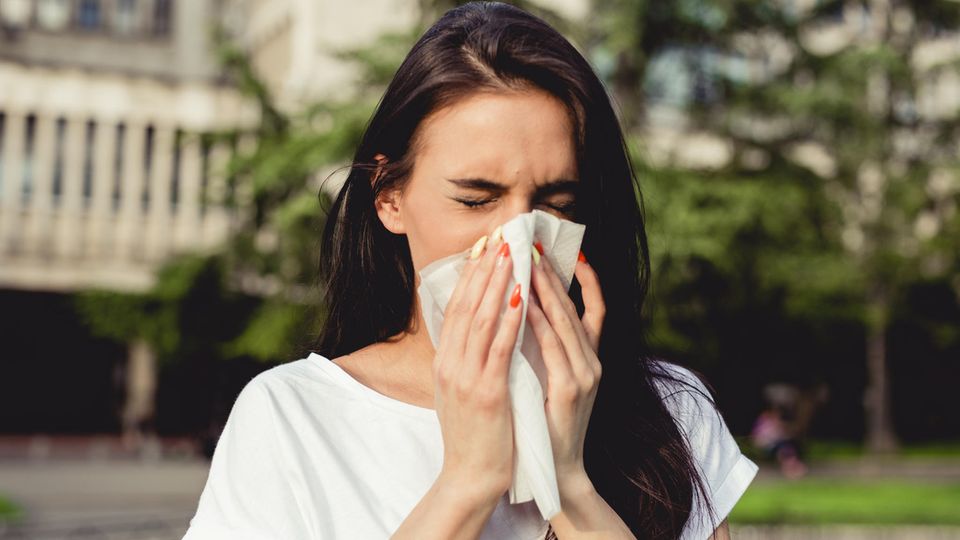 Sommergrippe: Eine Frau benutzt ein Taschentuch