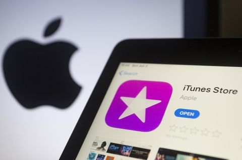 Auf einem Laptop ist der iTunes Store geöffnet. Im Hintergrund ist ein Apple-Logo zu sehen.