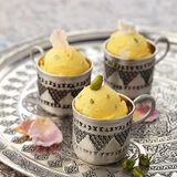 Gruß aus dem Orient      Zutaten:  165 g Zucker, 15 g Glukosepulver, 2 g Johannisbrotkernmehl, 1/4 TL gemahlener Safran, 500 ml frische Vollmilch, 300 ml flüssige Sahne (32% Fettgehalt), 1–2 TL Bio-Rosenwasser (alternativ 1–2 Tropfen Bio-Rosenöl), 20 g geschälte ganze Pistazienkerne      Zubereitung:  Den Zucker, das Glukosepulver, das Johannisbrotkernmehl und den Safran vermischen. Die Milch und die Sahne in einen Topf geben. Die trockenen Zutaten mit einem Schneebesen hineinrühren und die Mischung unter Rühren erhitzen, aber nicht aufkochen. Den Topf vom Herd ziehen und mit einem Stabmixer gut durchmixen. Die Eisgrundmasse abkühlen lassen, dann das Rosenwasser unterrühren und anschließend im Kühlschrank gut durchkühlen lassen. Die Eisgrundmasse aus dem Kühlschrank nehmen, mit einem Stabmixer nochmals aufmixen und in die Eismaschine umfüllen. Nach den Angaben des Herstellers ein cremiges Eis daraus herstellen. Kurz vor dem Ende des Vorgangs die Pistazienkerne in die Eismaschine geben und das Eis fertigstellen. Das fertige Eis in einen vorgekühlten, verschließbaren Becher umfüllen und verschlossen in das Gefrierfach stellen.