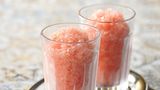 Wassermelonen-Granita      Zutaten:  100 g Zucker, 1 mittelgroße Wassermelone, 2–3 Spritzer frisch gepresster Zitronensaft, Abrieb von 1 unbehandelten Zitrone (optional)      Zubereitung:  Den Zucker mit 100 ml Wasser in einen Topf geben, unter Rühren aufkochen und etwa 10 Minuten köcheln lassen, bis sich der Zucker aufgelöst hat. Den Zuckersirup abkühlen lassen und im Kühlschrank gut durchkühlen. Die Wassermelone halbieren und das Fruchtfleisch aus der Schale schneiden. Dabei sorgfältig alle Kerne entfernen. Das Fruchtfleisch in grobe Stücke zerkleinern. Es werden 600 g reines Fruchtfleisch benötigt – diese Menge abwiegen und in einen Mixbecher mit hohem Rand geben. Das Wassermelonenfleisch mit dem Stabmixer pürieren. Den Zuckersirup, den Zitronensaft und gegebenenfalls den Zitronenabrieb unter das Wassermelonenpüree rühren. Diese Granita-Grundmasse in eine flache Gefrierbox füllen, sodass die Füllhöhe 3–4 cm nicht übersteigt. Die Form mit dem Deckel verschließen und waagerecht in den Gefrierschrank stellen. Im Abstand von je 30 Minuten mit einer Gabel alle Eiskristalle, die sich am Boden und an der Wand der Form gebildet haben, zur Mitte hin zusammenschieben. Nach etwa 3 Stunden sollte die gesamte Menge durchgefroren sein, die Granita ist dann servierfertig. Zum Servieren die Granita mit einem großen Löffel von der Oberfläche schaben und anrichten.