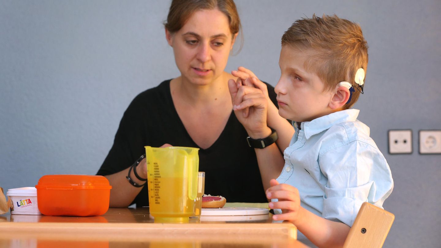 Erzieherin Stefanie Tröster sitzt in einer Wohngruppe des Blindeninstitutes mit dem taubblinden Lucas beim Frühstück