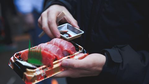 Mann mit einer Sushi Packung in der Hand