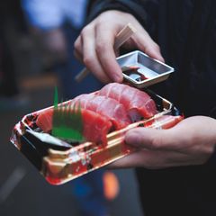 Mann mit einer Sushi Packung in der Hand