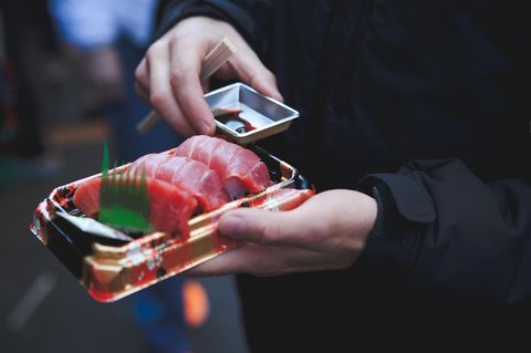 Mann mit einer Sushi Packung in der Hand