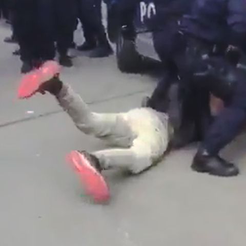 Polizisten fixieren einen Demonstranten am Boden