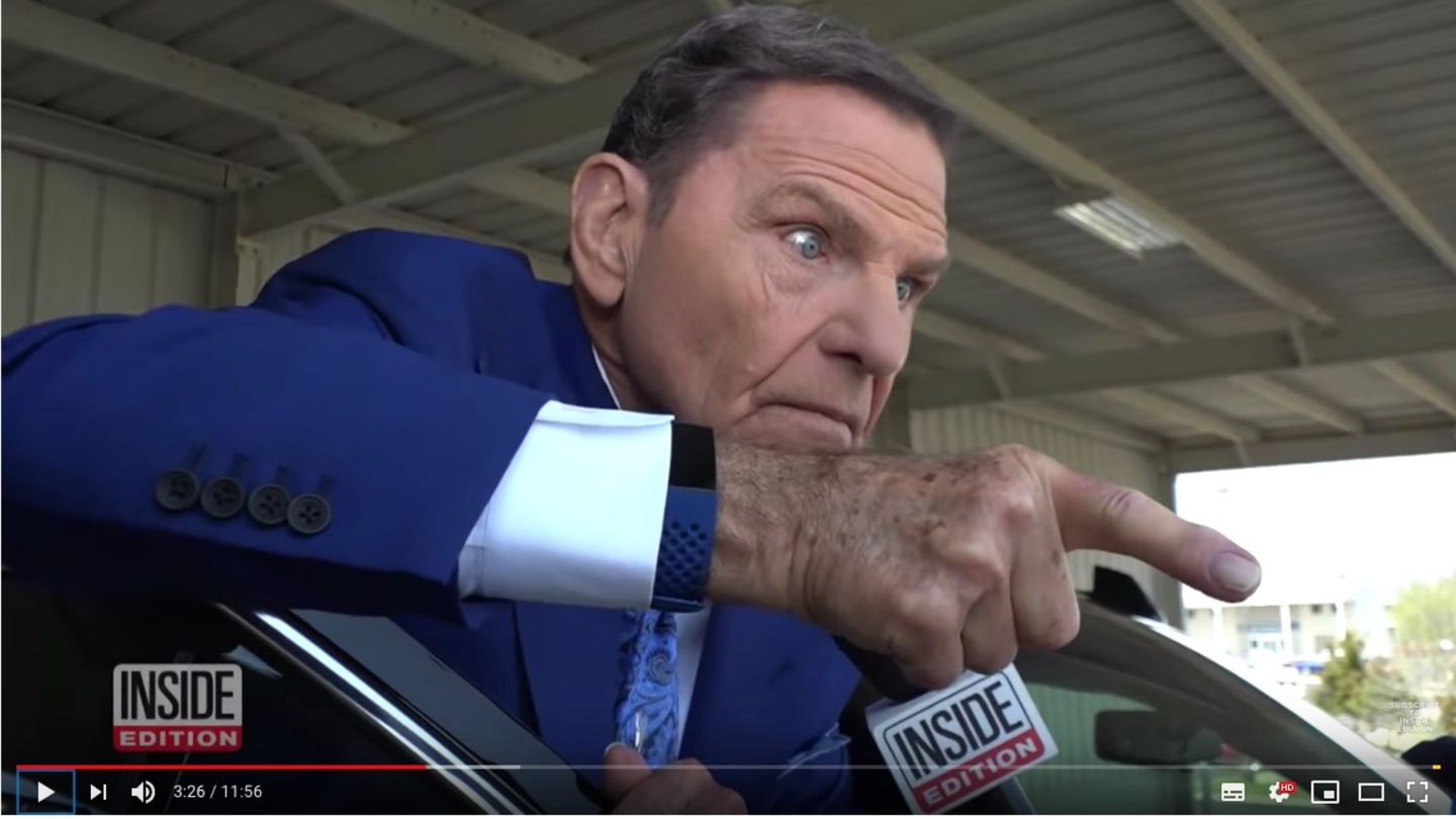 Kenneth Copeland steht in blauem Anzug vor seiner Autotür. Er zeigt mit dem Finger auf die Reporterin und schaut aggressiv.