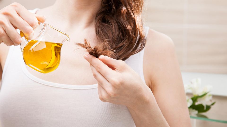 Öl versorgt die Spitzen mit Nährstoffen Frau ölt ihre Haare ein