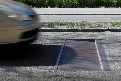 Ein Auto rast auf eine in der Straße eingelassene Stahlplatte zu