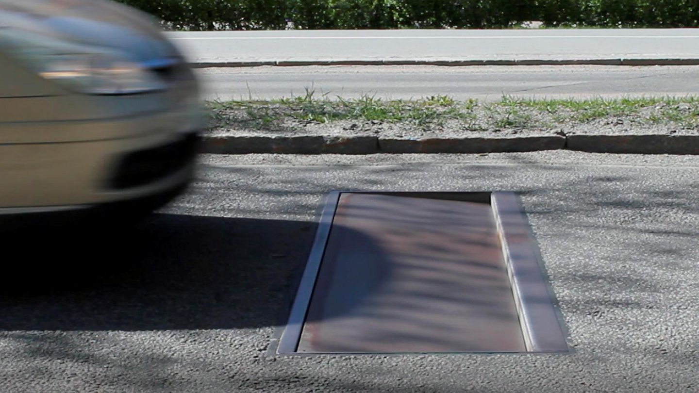 Ein Auto rast auf eine in der Straße eingelassene Stahlplatte zu