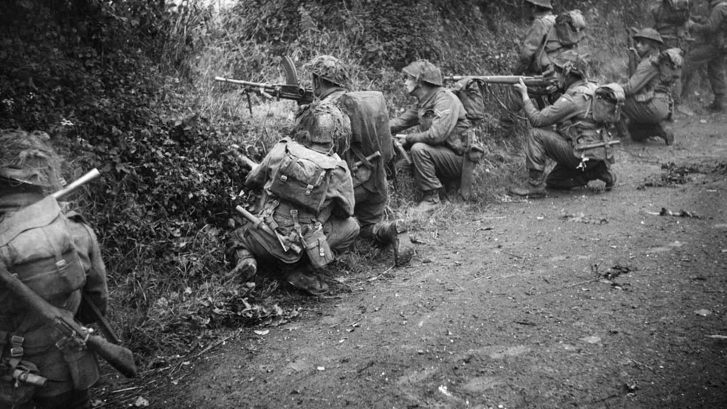 Alliierte Soldaten suchen Schutz hinter Wall und Hecke.