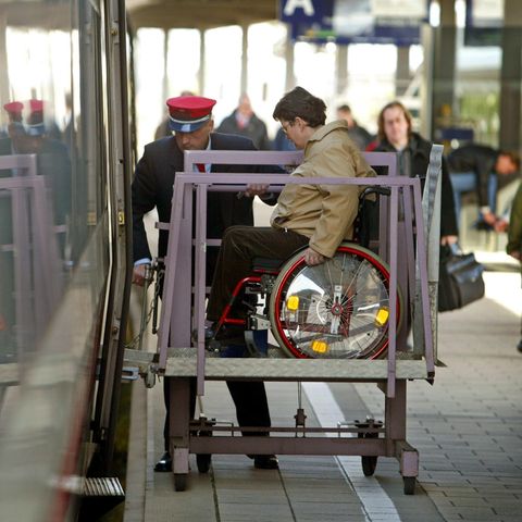 Ein Mitarbeiter der Deutschen Bahn hilft einer Frau, in den Zug zu gelangen